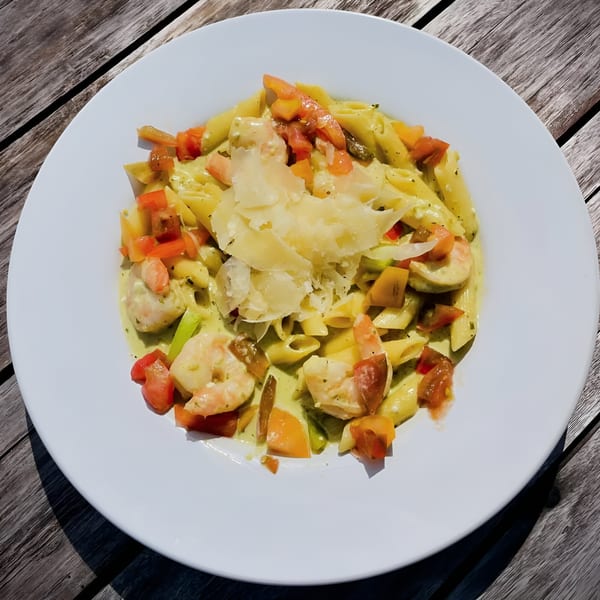 Penne pasta with shrimp, diced tomatoes, and shaved parmesan cheese in a creamy sauce.